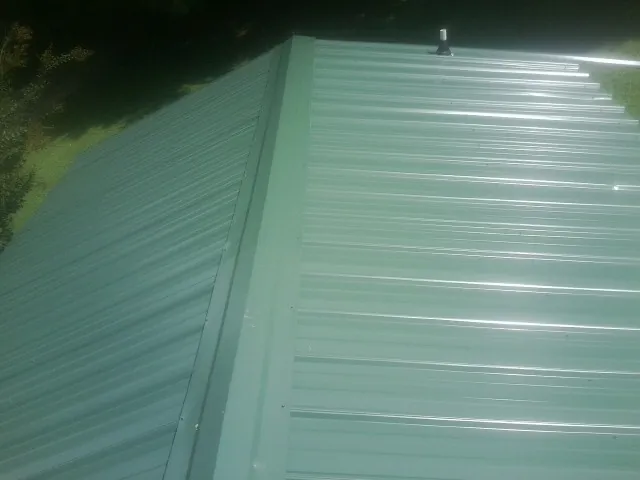 New green metal panels meeting at the ridge of a roof — Flat Roof Repair work by our crew in Guide Rock