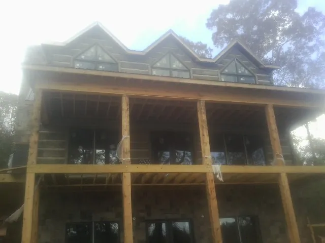 Dormers and porch framing on a large log home under construction — Roof Coating work by our crew in Guide Rock
