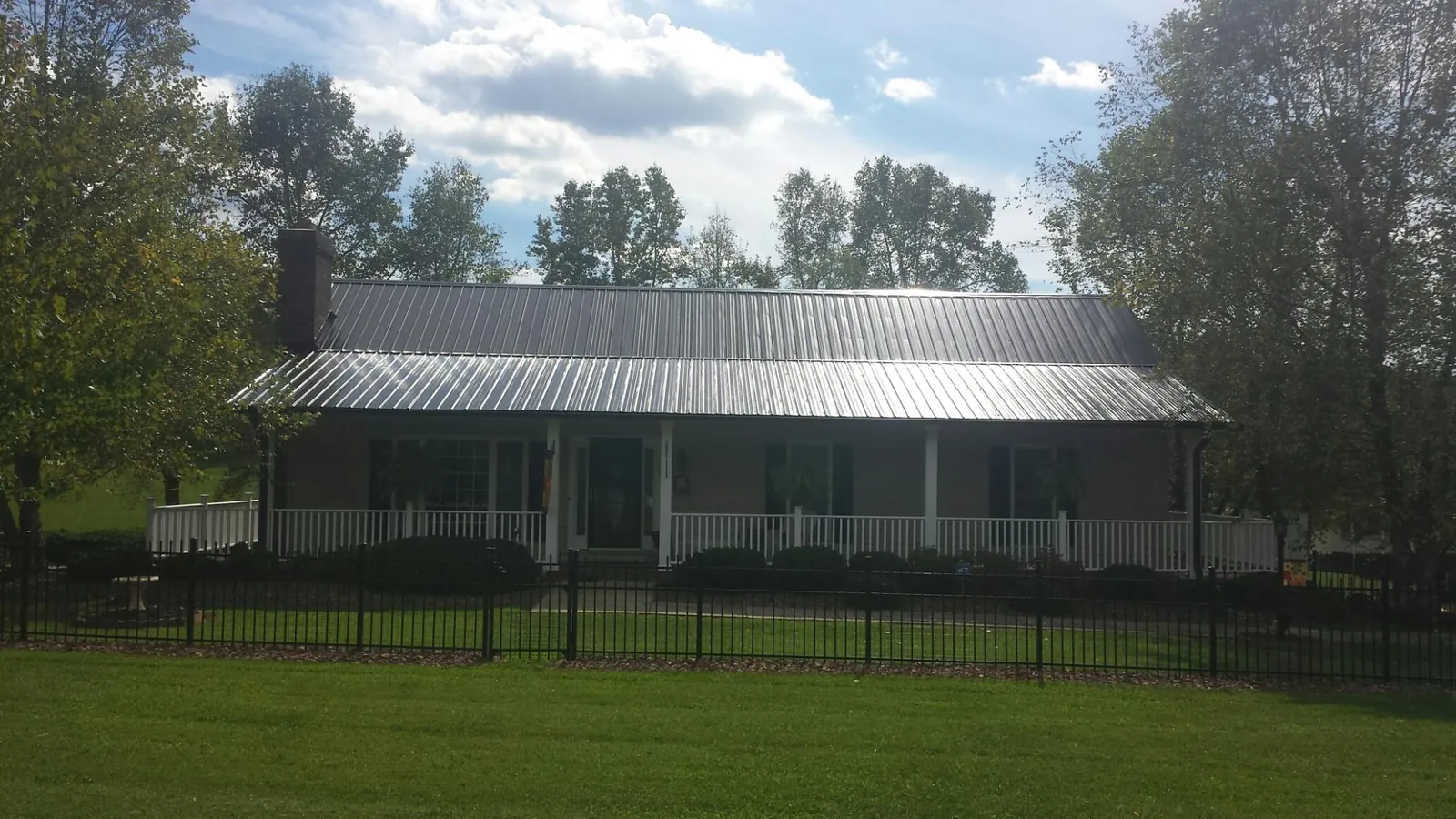 Gray metal roof on a brick ranch with a full width front porch — Gutter Guard Installation work by our crew in Guide Rock