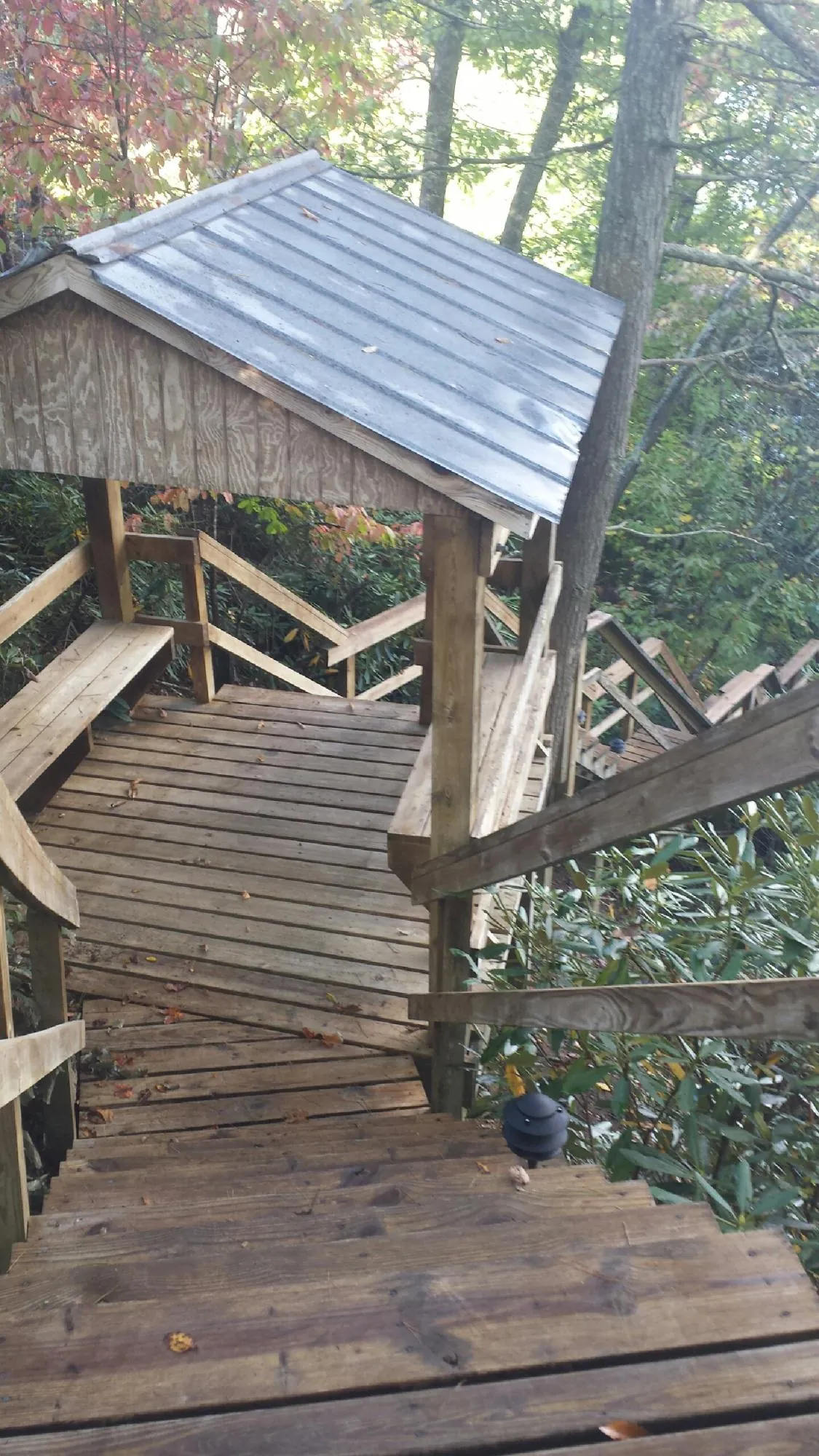 Metal roofed shelter over wooden steps on a wooded walkway — Skylight Repair & Installation work by our crew in Guide Rock